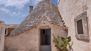 A stone building with a tiled roof, a door, and a potted plant. - iCONICO - Authentic Trulli Experience (Cisternino)