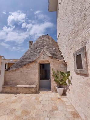 Un bâtiment en pierre avec un toit en tuiles, une porte et un pot de fleurs.