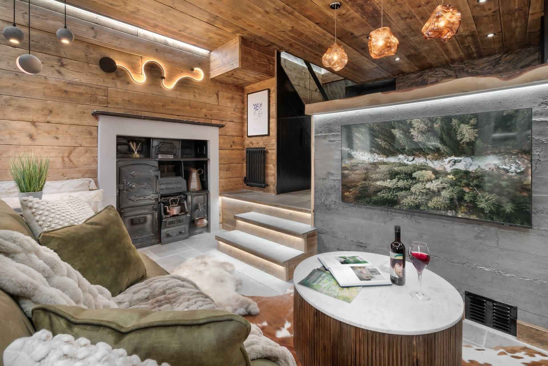 Una sala de estar acogedora con chimenea, techo de madera y una gran pared con acuario.