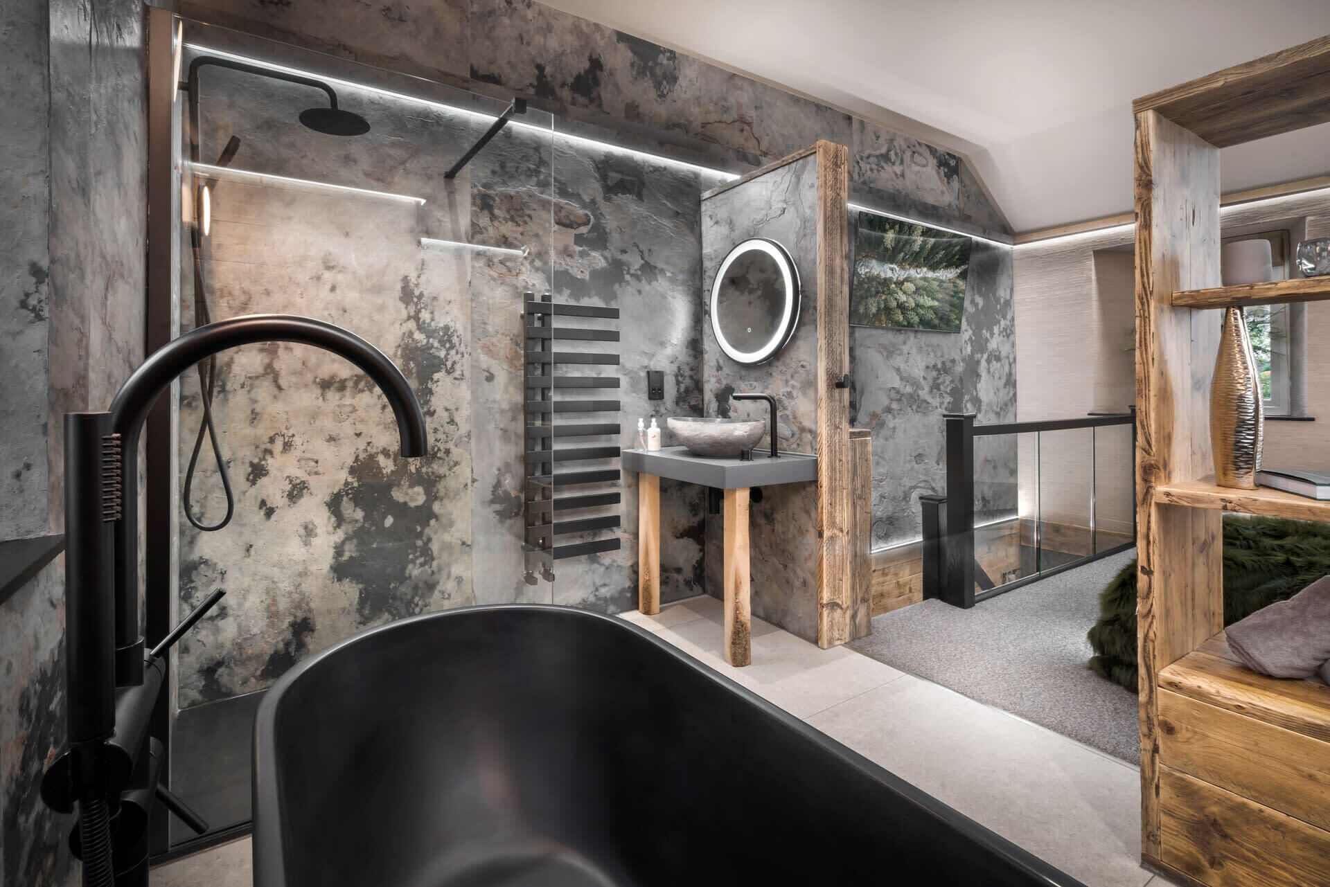 A modern bathroom with a freestanding bathtub, a large mirror, and a stone sink.