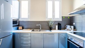 Eine moderne Küche mit grauen Schränken, einer Edelstahl-Spüle und einem eingebauten Backofen.