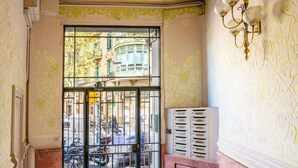 Ein Innenraum mit einer dekorativen Decke, einer großen Glasdoor mit einem Metallgitter und einer an der Wand montierten Leuchte.