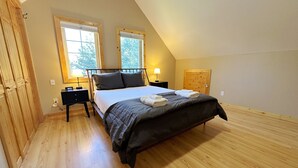 A bedroom with a bed, two bedside tables, a nightstand, a wooden wardrobe, and two windows. - Inviting Family Retreat w/Hot Tub in Driggs (Driggs)