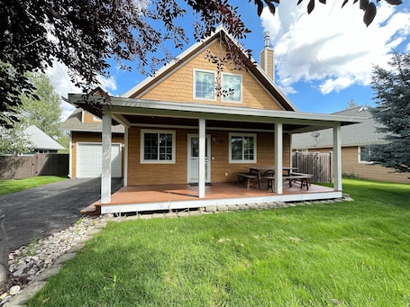A two-story house with a covered porch, a garage, and a well-maintained lawn.