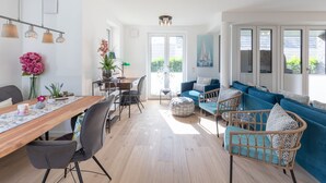 A bright, open-plan living space with a dining area, seating area, and large windows providing natural light.