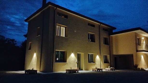 A multi-story building with illuminated windows and a flat roof. - Agriturismo Le Crede 1930  (Portogruaro)