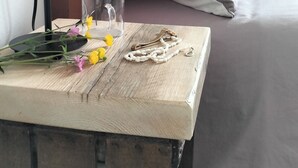 A wooden bedside table with a lamp, a glass, a necklace, and flowers. - Agriturismo Le Crede 1930  (Portogruaro)