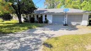 Une maison de plain-pied avec un garage, une allée et un panier de basketball.