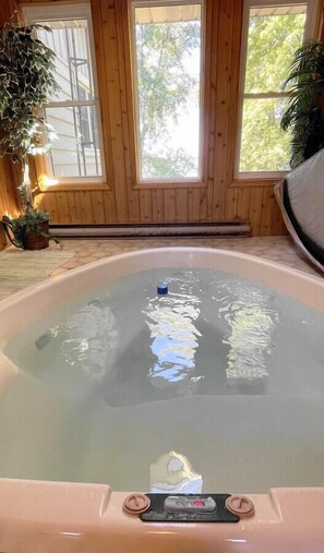 A hot tub in a room with wooden walls and large windows.