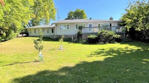 A single-story house with a front porch, a small front yard, and a tree to the left.