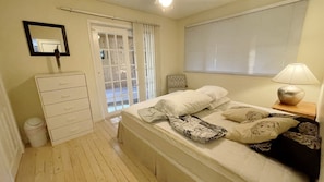 A bedroom with a bed, a dresser, a mirror, a window with blinds, and a lamp. - Charming Lakeside Retreat: Cozy and Convenient on Chemong Lake (Lakefield)