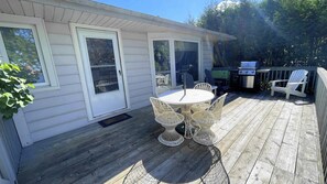 Un patio couvert avec un barbecue, une table et des chaises d’extérieur.
