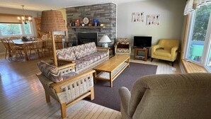 A living room with a fireplace, a television, and a dining area with chairs and a table.