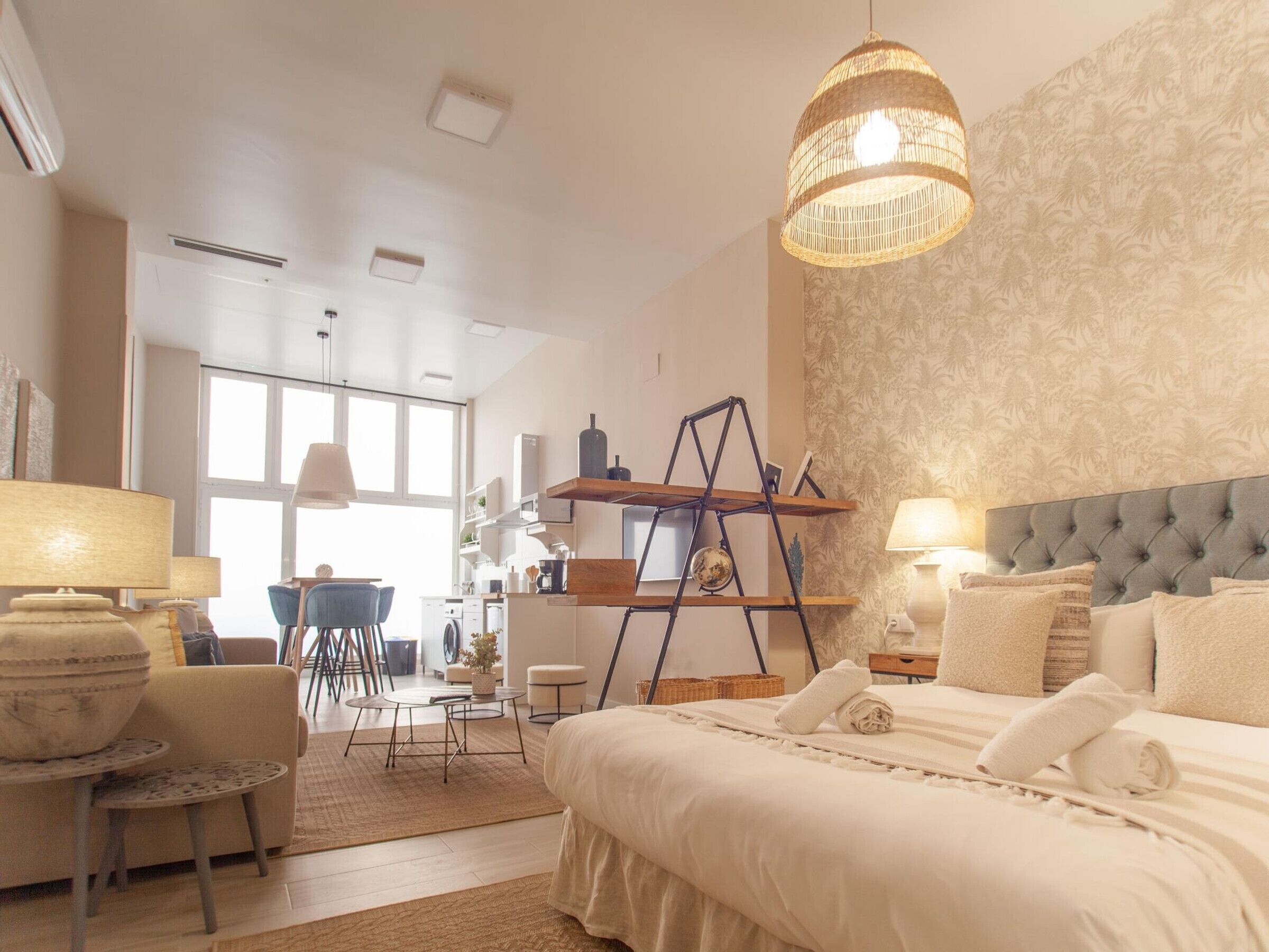 Habitación de hotel con una cama grande, un escritorio, una silla, una lámpara colgante y vista al área de la cocina.