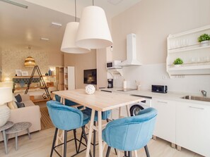 Uma cozinha moderna com mesa de madeira, cadeiras azuis e armários brancos.