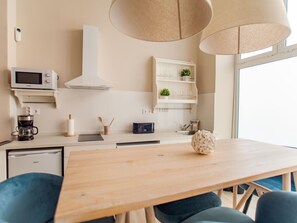 Uma cozinha moderna com micro-ondas, máquina de café e uma mesa de jantar de madeira.