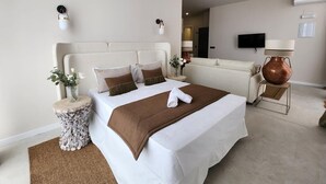 Une chambre d’hôtel moderne avec un grand lit, une petite table d’appoint, un canapé et un téléviseur.