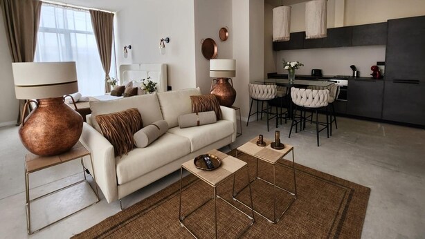 Un salon moderne avec un canapé, une table basse et des lampes. Il y a également un coin cuisine avec une table à manger et des chaises.