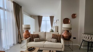 Un salon moderne avec un canapé beige, deux lampes en cuivre et une table basse.
