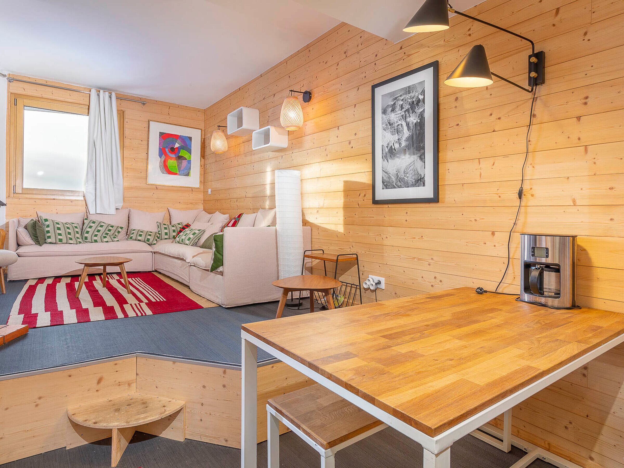 A cozy living room with a wooden floor, a sofa, a coffee table, and a dining table.