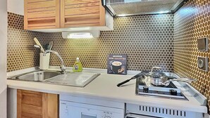 A compact kitchen with wooden cabinets, a stainless steel sink, and a microwave. - Spacious 2BR in Val d'Isère with Two Bathrooms (Val-d'Isère)
