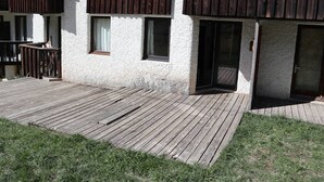 Een gebouw met een houten terras, een balkon en een schuifdeur met glas.