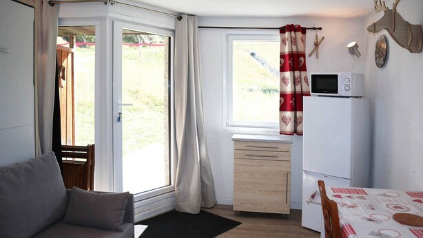 Een knus woongedeelte met een bank, een tafeltje, een kitchenette en een eethoek.