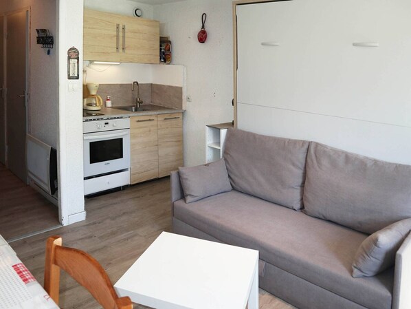 Un espace de vie compact comprenant un coin cuisine, un canapé et une petite table.