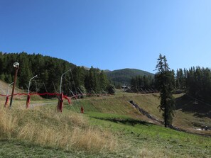 Un paysage rural caractérisé par un ciel dégagé, une route sinueuse et une chaîne de montagnes lointaine.