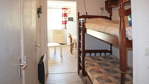 Een kamer met stapelbedden, een witte tafel en een stoel.