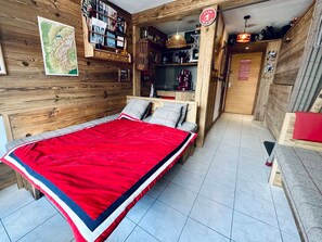 Ein Zimmer mit Holzboden, einem Bett, einem Bücherregal, einer Karte und einem Schild, das auf eine Bar hinweist.
