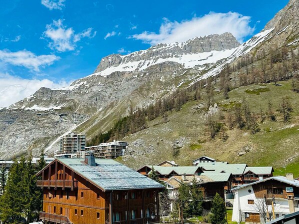 A mountain resort with wooden buildings, a ski lift, and snow-capped peaks.