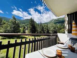 A balcony with a table set for dining, overlooking a mountainous landscape. - Cozy Mountain Studio with Balcony, Near Ski Lifts and Shops, Sleeps 4 (La Salle-les-Alpes)