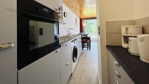 A compact kitchen with a built-in oven, a washing machine, and a coffee machine.
