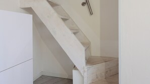 A white wooden staircase with a metal handrail, leading to a landing. - La Cà Fiera 23B. (Bologna)