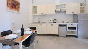 Una cocina moderna con armarios blancos, una mesa de comedor lista para cuatro personas y una cafetera.