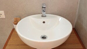 Un lavamanos blanco con grifo de cromo sobre un mueble de madera.