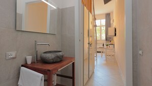 A modern bathroom with a stone sink, a mirror, and a wooden vanity. - La Cà Fiera 11E. (Bologna)