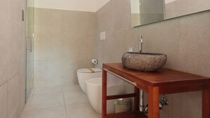 A modern bathroom with a glass shower enclosure, a white toilet, and a wooden vanity with a stone sink. - La Cà Fiera 11E. (Bologna)