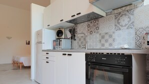 A modern kitchen with white cabinets, a built-in oven, and a patterned backsplash. - La Cà Fiera 11E. (Bologna)