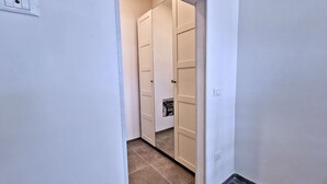 Un corridoio con una porta bianca che dà su una stanza con pavimento piastrellato.
