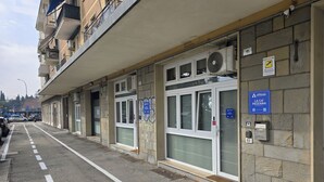 Un edificio con diversi locali commerciali al piano terra, tra cui un bancomat e un cartello con su scritto 'La Ca' Pezzana'.