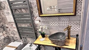 Un bagno con bidet, lavabo con bacino in pietra, piano in legno e portasciugamani.