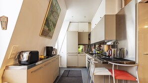 A compact kitchen with a toaster, kettle, and bar stools.
