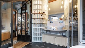 A modern bathroom with a glass shower enclosure, a built-in sink with a mirror, and a storage cabinet.