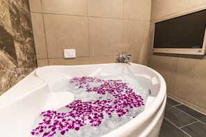 A bathtub filled with water and purple flower petals. - Petit Bali Forest Shinjuku Sanchome (Tokyo)