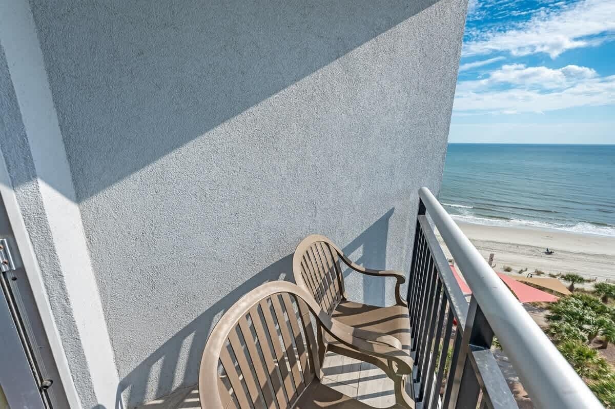 Ein Balkon mit zwei Stühlen mit Blick auf einen Strand.