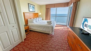 Une chambre d’hôtel avec un lit, un bureau, une vue sur l’océan et une enseigne indiquant « Big Fish Rental ».