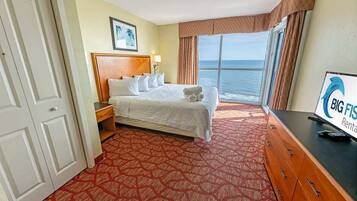 Habitación de hotel con cama, escritorio y vista al océano, además de un cartel de Big Fish Rental.