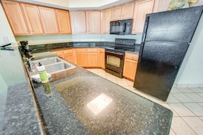 Kitchen area with a refrigerator, microwave, sink, oven, and stovetop.